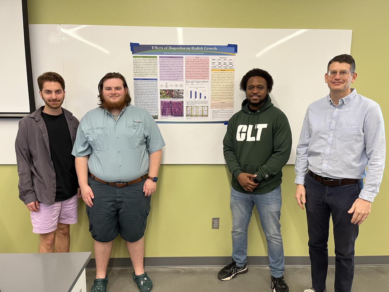 Cole Lyons and UNC Charlotte classmates standing with an ibuprofen and radish growth research poster.